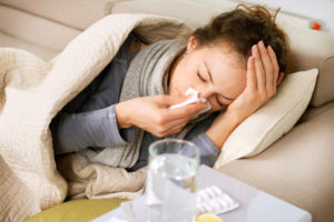 sick woman on couch blowing nose