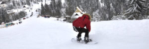 Person snowboarding down hill in squatting position