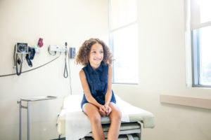 Child sitting on hospital table waiting for vaccination