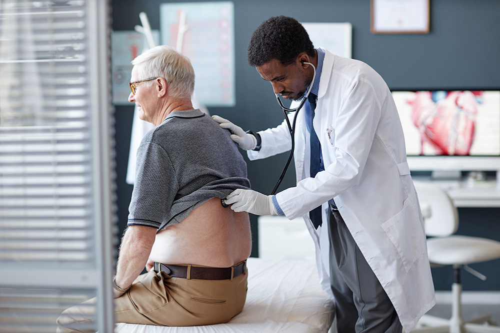 Doctor using stethoscope to examine senior patient's heart and breathing during medical checkup in clinic