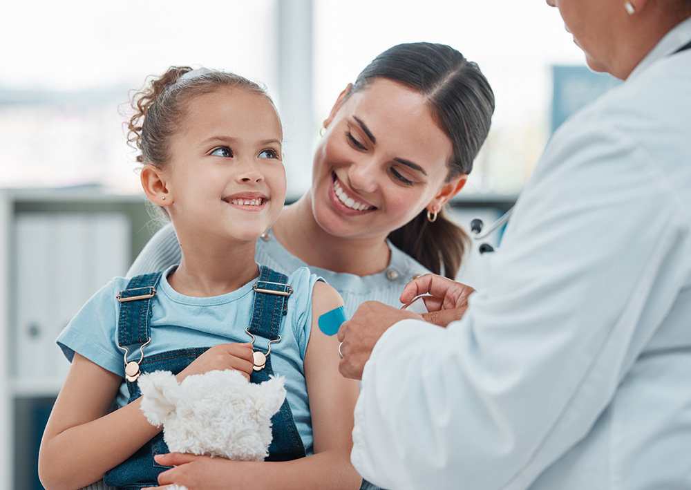 A mother and child in a doctor's office. A doctor is attending to a smiling child.