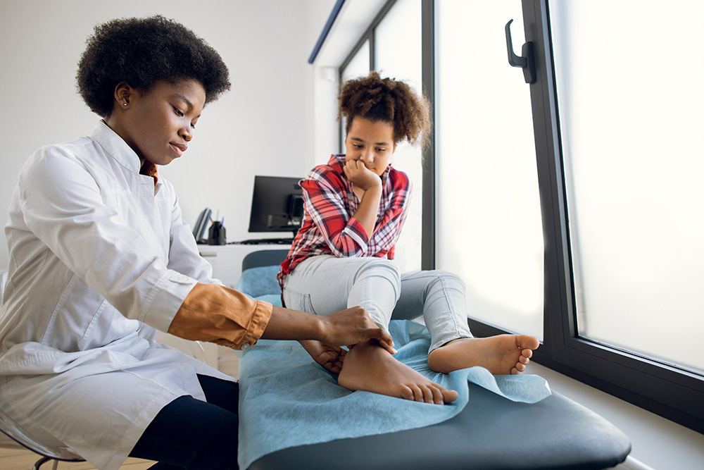 Doctor examining a child’s ankle injury in an urgent care clinic.